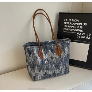 Detail showing blue denim fabric with silver sequin wave patterns and brown leather straps