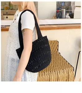 Detailed view of hand-woven black knit tote bag with subtle sequins in a cafe setting