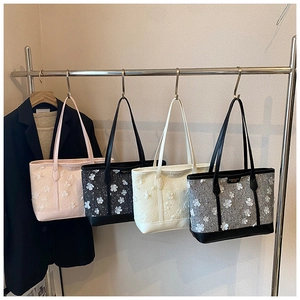 Detail view of four tweed tote bags with 3D floral appliques and faux leather handles