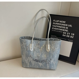 Detail of light blue sequin tote bag with silver wave texture and slender handles