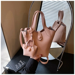 Detail of pink lychee leather bucket bag with mini pendant and adjustable strap
