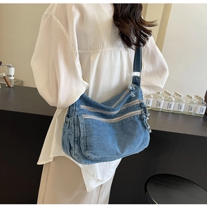 Detail view of denim tote bag with multiple functional zippers and side pockets