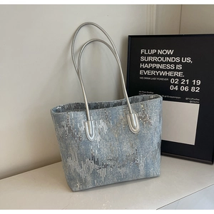 Detail of blue denim tote bag with silver sequin wave pattern and thin metallic straps