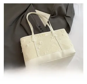 Detailed macro view of cream tote bag with 3D floral accents and gold logo branding