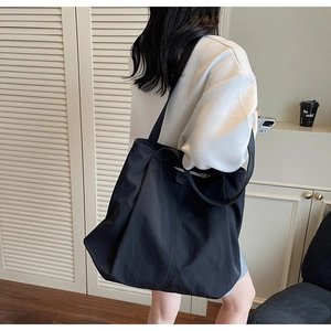 Rear view of a black large capacity canvas tote bag worn on shoulder for daily commute