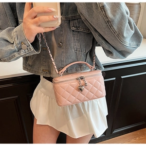 Detailed view of pink quilted leather mini bag with silver chain strap and heart pendants