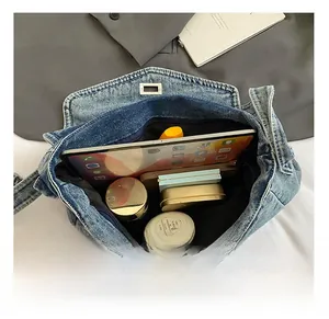 Vista interna che mostra la grande capacità della borsa tote in denim con tablet e oggetti