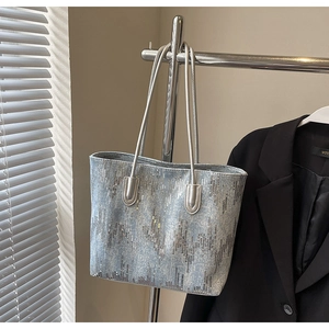 Close-up of a large sequin tote bag with shimmering vertical stripes and leather straps