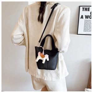 Litchi pattern black bucket bag shown on model with a colorful leather horse charm