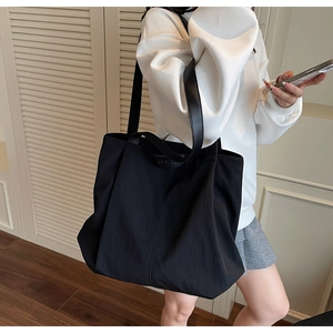 Detail of black large capacity nylon tote bag with leather strap on a model
