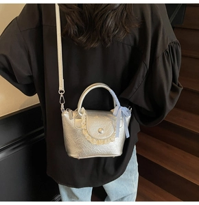 Détail du sac bandoulière argenté plissé avec bordure en dentelle et nœud à carreaux bleus