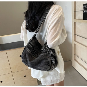 Detail of multi-zipper black denim tote bag with vintage washed texture on shoulder