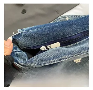 Dettaglio della cerniera in metallo argentato su una borsa tote in denim blu lavato
