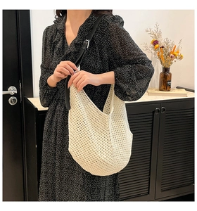 Detailed view of a white knitted mesh tote bag with an adjustable black leather strap