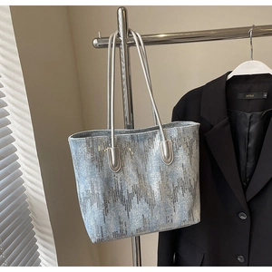 Detail view of denim tote bag featuring silver sequin geometric patterns and slim straps