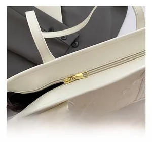 Close-up of golden metal zipper and floral embroidery on a minimalist tote bag