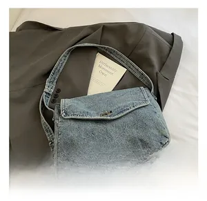 Dettaglio borsa a tracolla in denim blu lavato con chiusura a scatto argentata