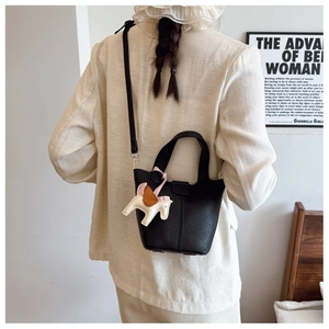 Detail of black textured leather bucket bag with horse charm and detachable strap