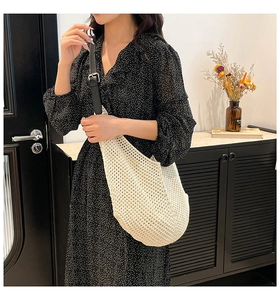 Detail of crochet knit beach bag with black faux leather strap on model in polka dot dress