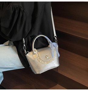 Détail du mini sac seau argenté métallisé avec bordure en dentelle et nœud à carreaux