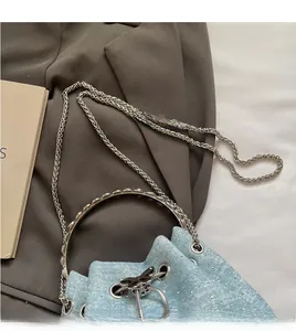 Detail of light blue denim bucket bag with sparkling rhinestones and silver bow charm