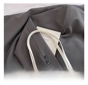 Detail of minimalist cream tote bag with brand logo tag and premium fabric texture