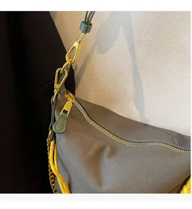 Close-up of smooth metal zipper and green leather accents on brown nylon bag