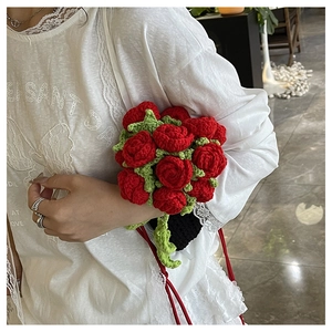 Detail of hand-knitted red rose bouquet with crochet texture and green leaves
