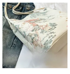 Close-up of intricate Chinese-style embroidery on a white bucket bag with fine details