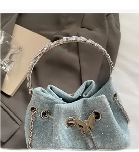 Close-up of light blue denim bucket bag featuring rhinestone decor and a silver butterfly buckle