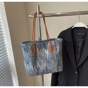 Detail view of navy sequined tote bag fabric with brown leather straps on a hanger