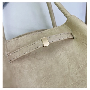 Macro-detail van beige leren tas met crinkle textuur en gouden metalen gesp
