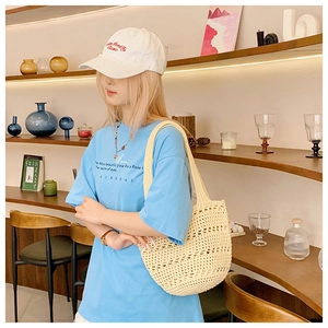 Detail of hollow woven straw tote bag in creamy white with thick braided handles