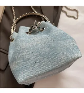 Detail of light blue denim bucket bag with silver sparkles and pearl ring handle