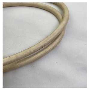 Detail van de lichtbeige handgrepen met krokodillenprint en stiksels op de draagtas