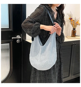 Detail of light blue crochet hobo bag with hollow knit pattern and slim black leather strap