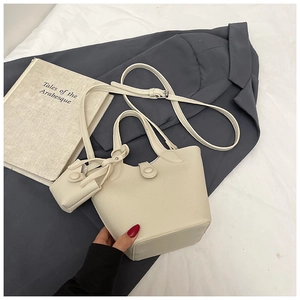 Detail of off-white lychee grain leather bucket bag with top handle and coin purse charm