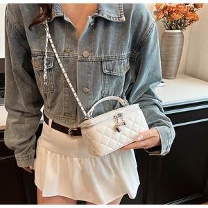 Detailed close-up of a white quilted crossbody bag with heart pendant and chain strap