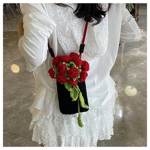 Detail of crochet bucket bag with red roses worn over a white lace dress by a model
