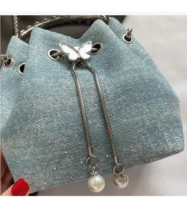 Detail of light blue denim bucket bag with sparkling rhinestones and pearl drawstring