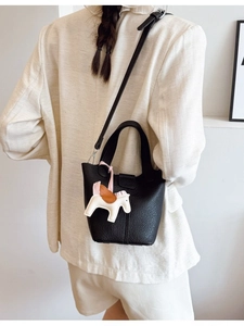 Classic black leather bucket bag with top handle, long strap and decorative pony charm