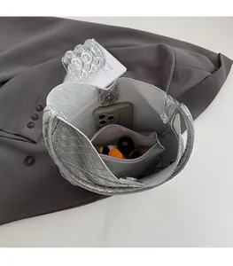 Vue de dessus du sac cabas tressé argenté montrant l'intérieur et sa pochette assortie