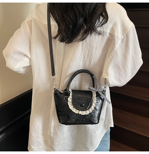 Détail du mini sac seau noir avec dentelle et nœud à carreaux sur cuir verni texturé