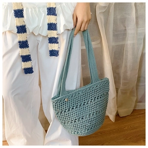 Detail of teal crochet hollow knit handbag with intricate woven patterns and metal clasp