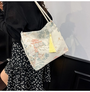 Detailed view of traditional Chinese embroidery and yellow tassel on cream tote bag