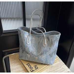 Detailed shot of light blue denim tote bag with silver sequins and metallic handles