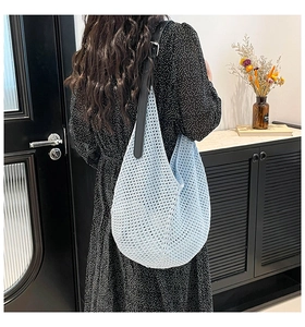 Detail of light blue knit crochet bag with black leather strap and metal buckle