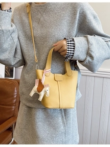 Bright yellow pebbled leather bucket bag with top handle and horse charm accessory