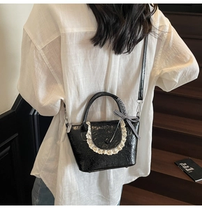 Détail du sac en cuir verni plissé noir avec bordure dentelle et nœud à carreaux sur un modèle