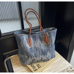 Detailed view of blue tote bag with silver sequins and durable brown leather straps